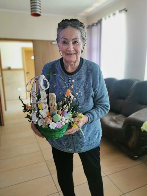 Seniorka trzyma wykonany własnoręcznie wielkanocny koszyczek z zajączkiem, pisankami i baziami w CuratioW w Rajczy