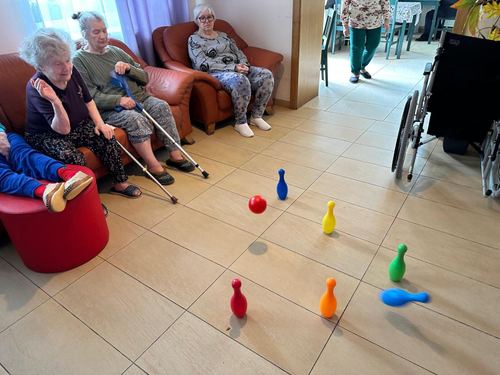 Seniorzy grają w kręgle z kolorowymi pinami na podłodze świetlicy CuratioW w Rajczy