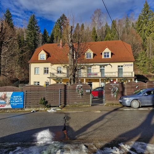 Frontowa elewacja domu seniora CuratioW w Rajczy w słoneczny zimowy dzień, ogrodzenie i auto przy bramie