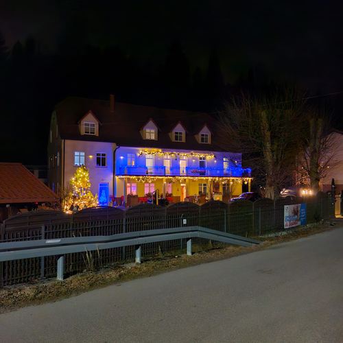 Budynek CuratioW widziany z drogi nocą, kolorowo iluminowana fasada, choinka przy wejściu i ogrodzenie z barierą przy ulicy