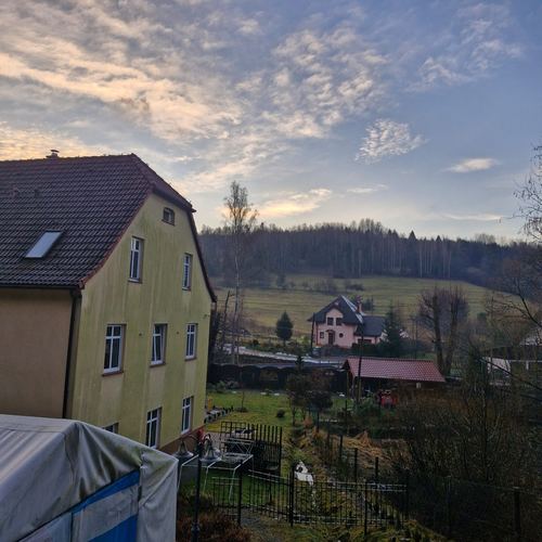 Widok znad domu CuratioW na żółtą sąsiednią willę i zalesione wzgórza Beskidu Żywieckiego o zmierzchu