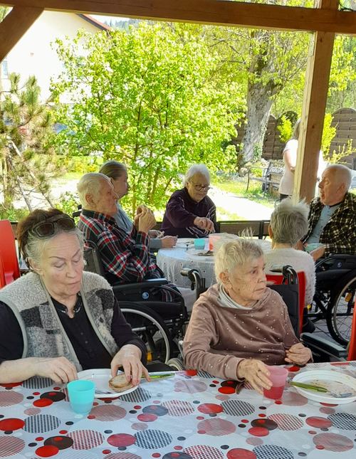 Mieszkańcy Domu Aktywnego Seniora CuratioW przy kawie i przekąsce w altanie wśród zieleni