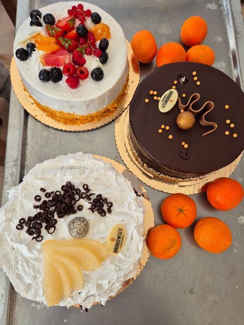 Trzy torty na blasze w kuchni CuratioW, owocowy, czekoladowy i śmietanowy, obok mandarynki