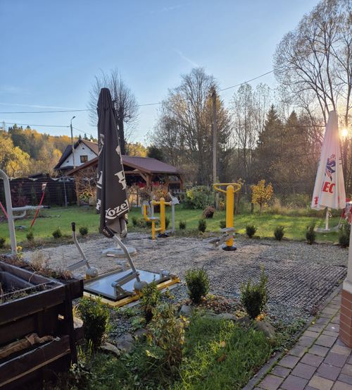 Siłownia plenerowa CuratioW o zachodzie słońca jesienią, złożony parasol i zaschnięte trawy, góry w tle